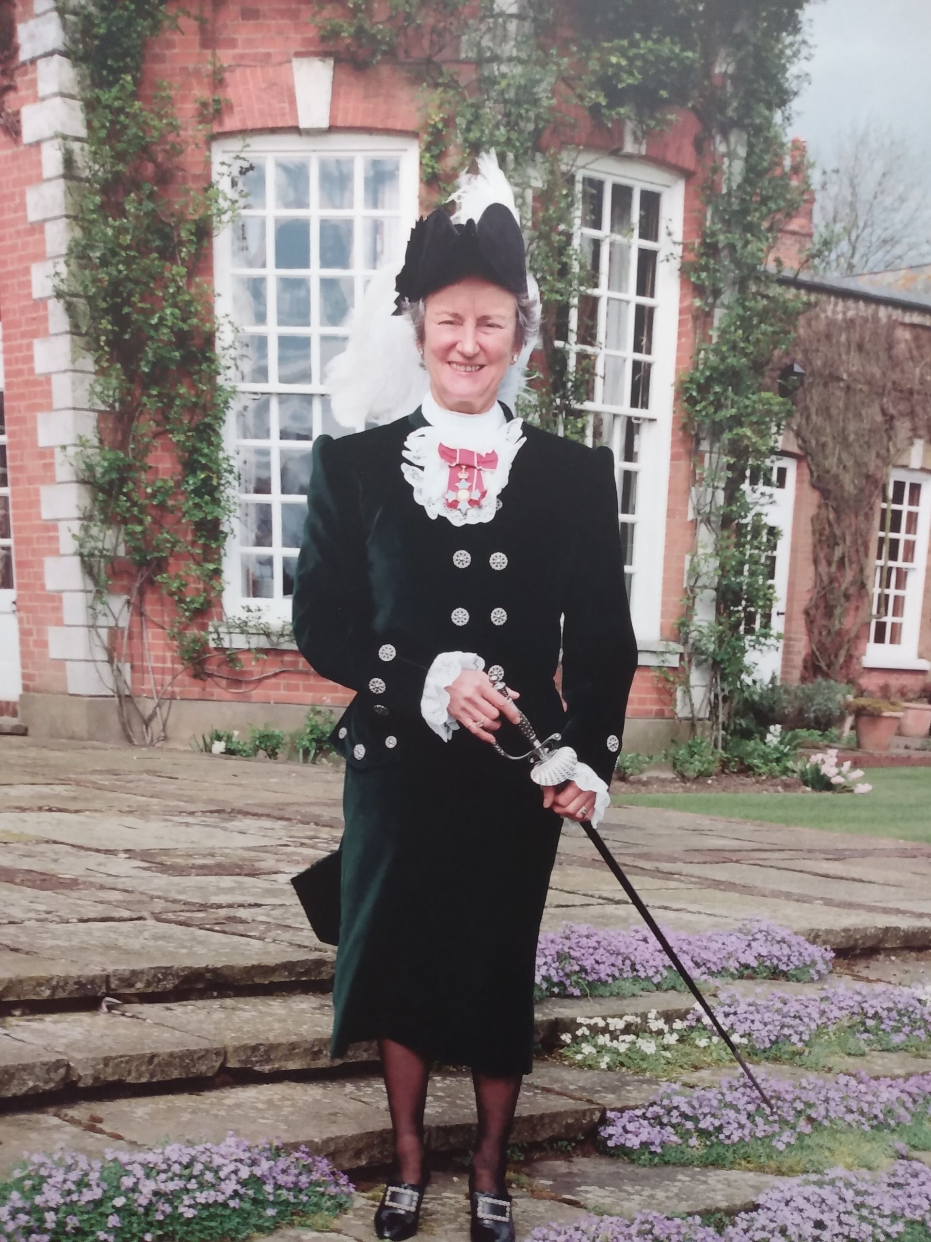 A woman holding a cane in front of a brick building