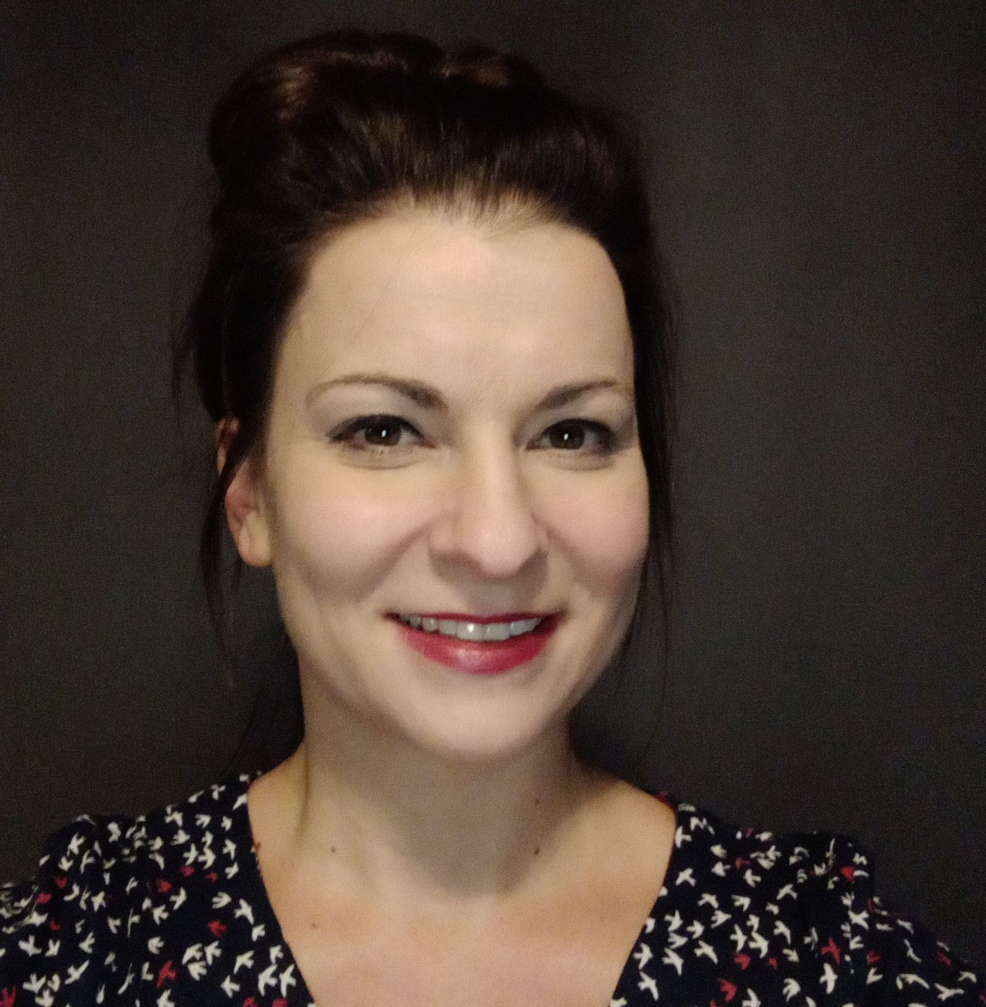 A woman with her hair in a bun is smiling for the camera