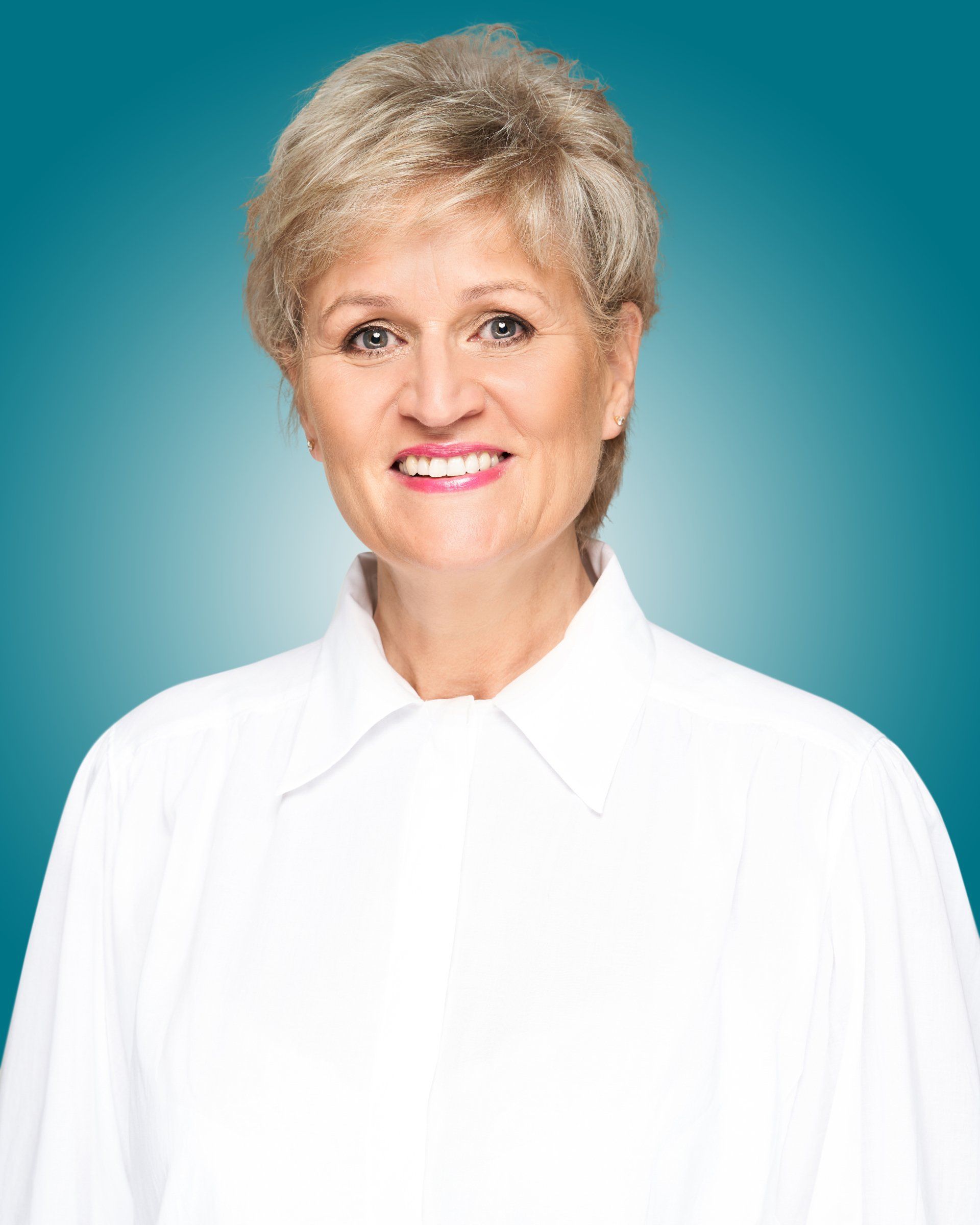 A woman in a white shirt is smiling for the camera against a blue background.