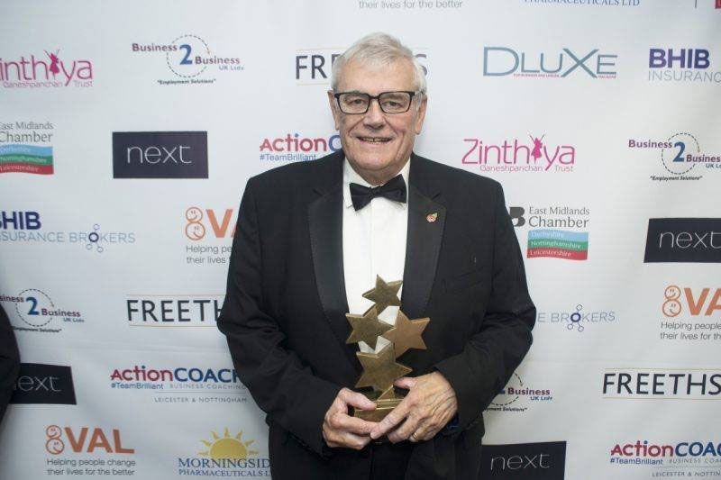 A man in a tuxedo and bow tie is holding a trophy.