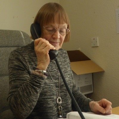 An image of Dorothy Tomlinson answering the phone in the Hope Office