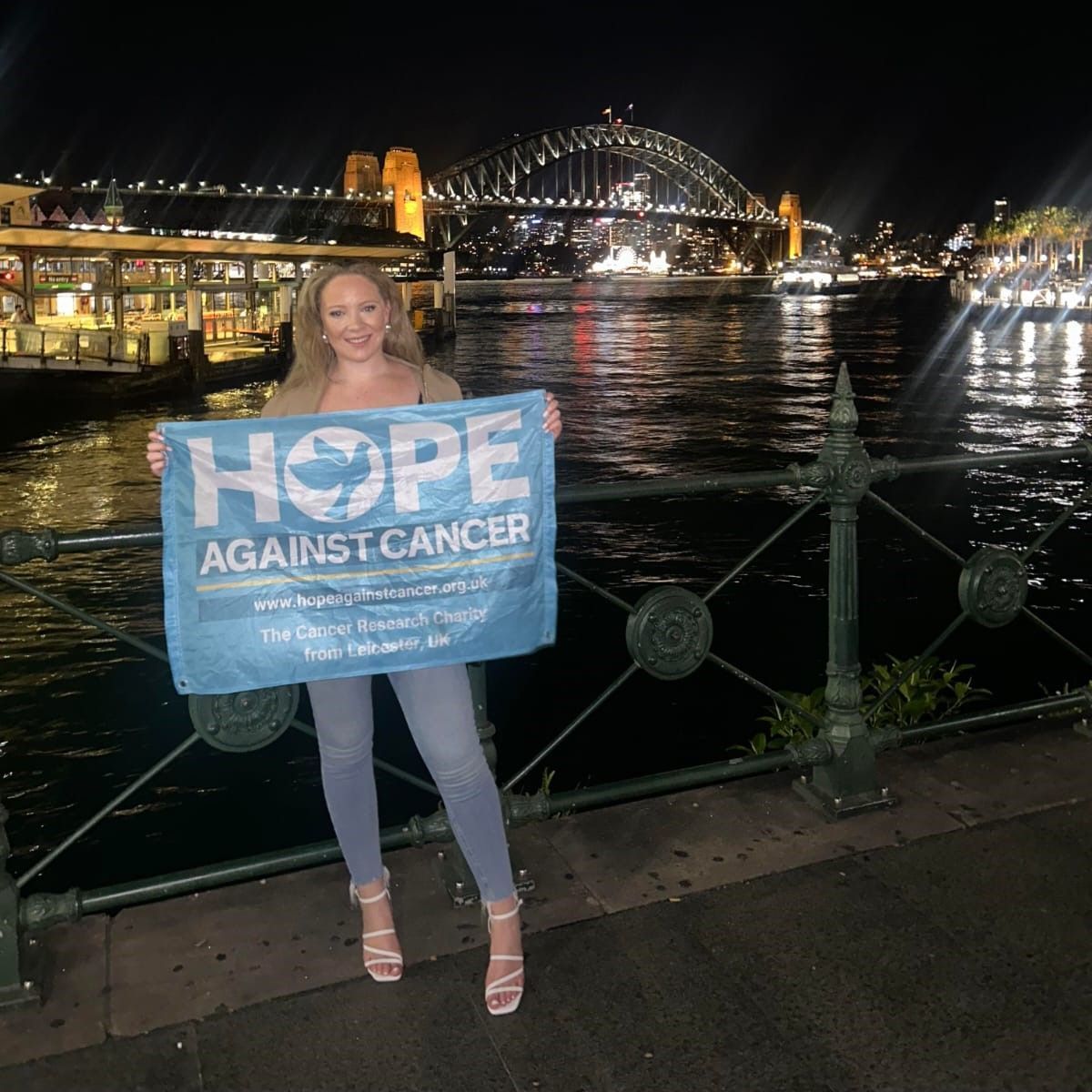 A woman is holding a sign that says hope against cancer