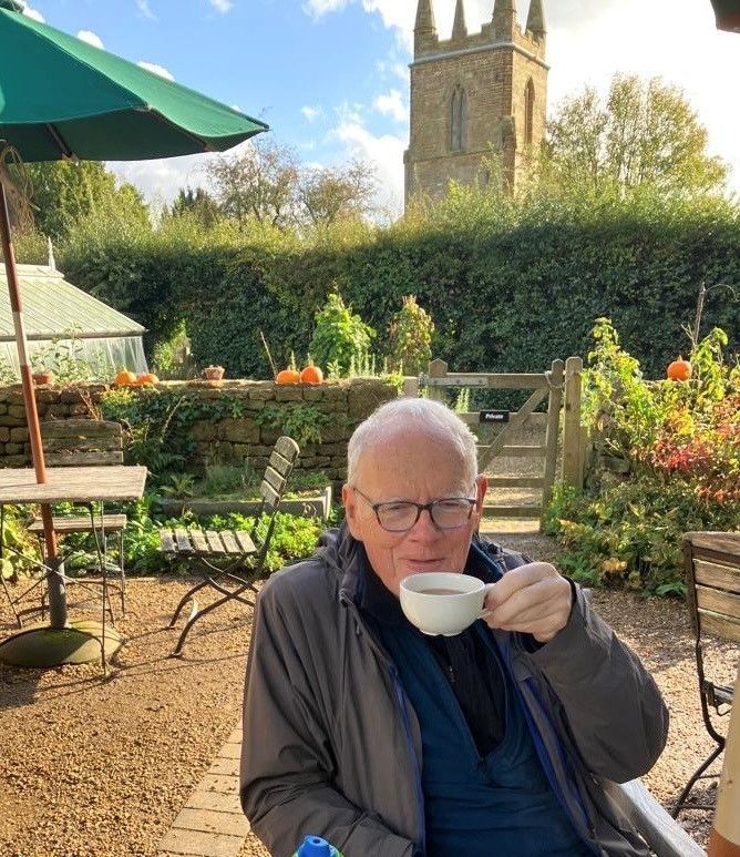 A man with glasses is drinking a cup of coffee outside