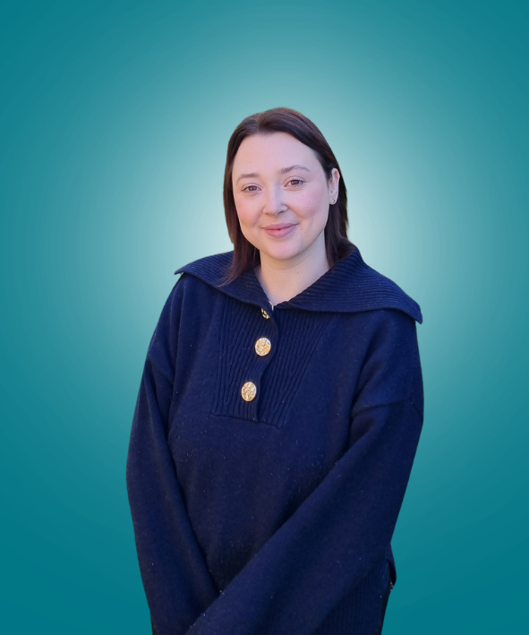 A man in a white shirt is standing with his arms crossed and smiling.