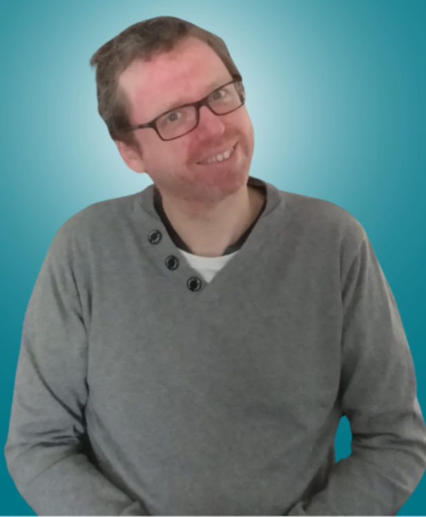 A man wearing glasses and a grey sweater is smiling