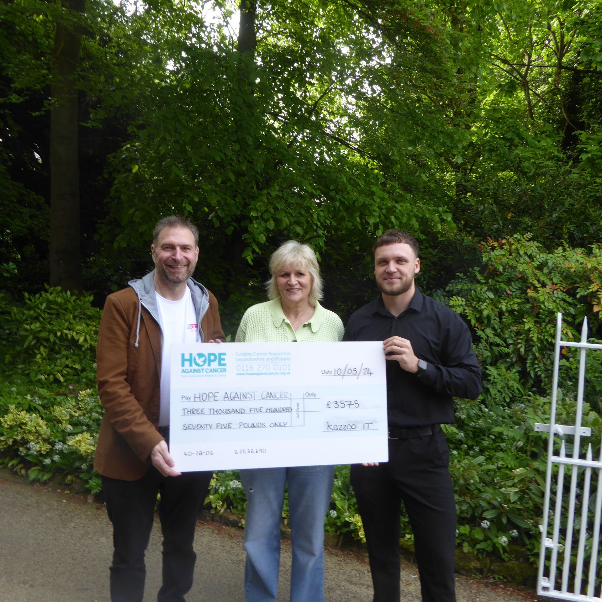 Three people holding a cheque that says hope on it