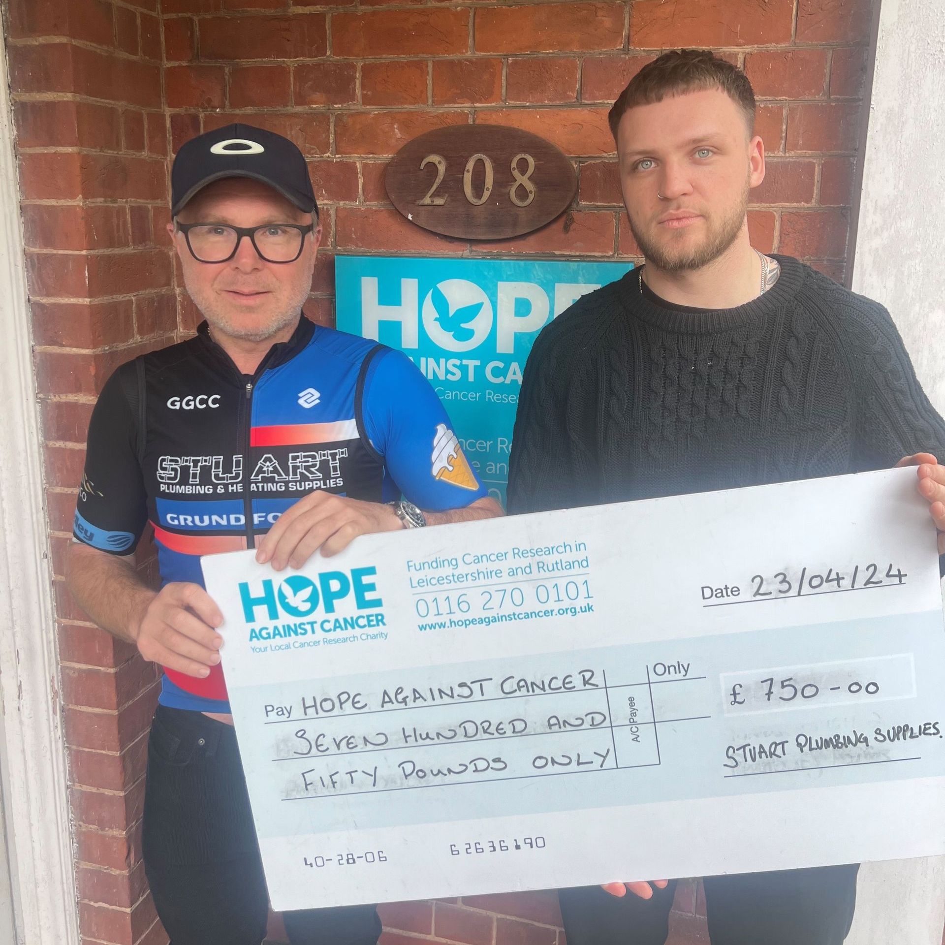 Two men holding a cheque for hope against cancer