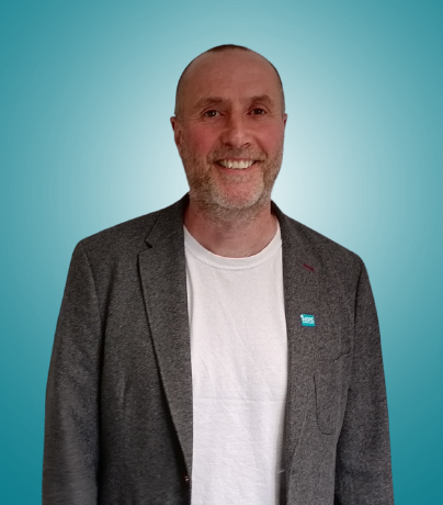 A bald man in a blue shirt is smiling for the camera.