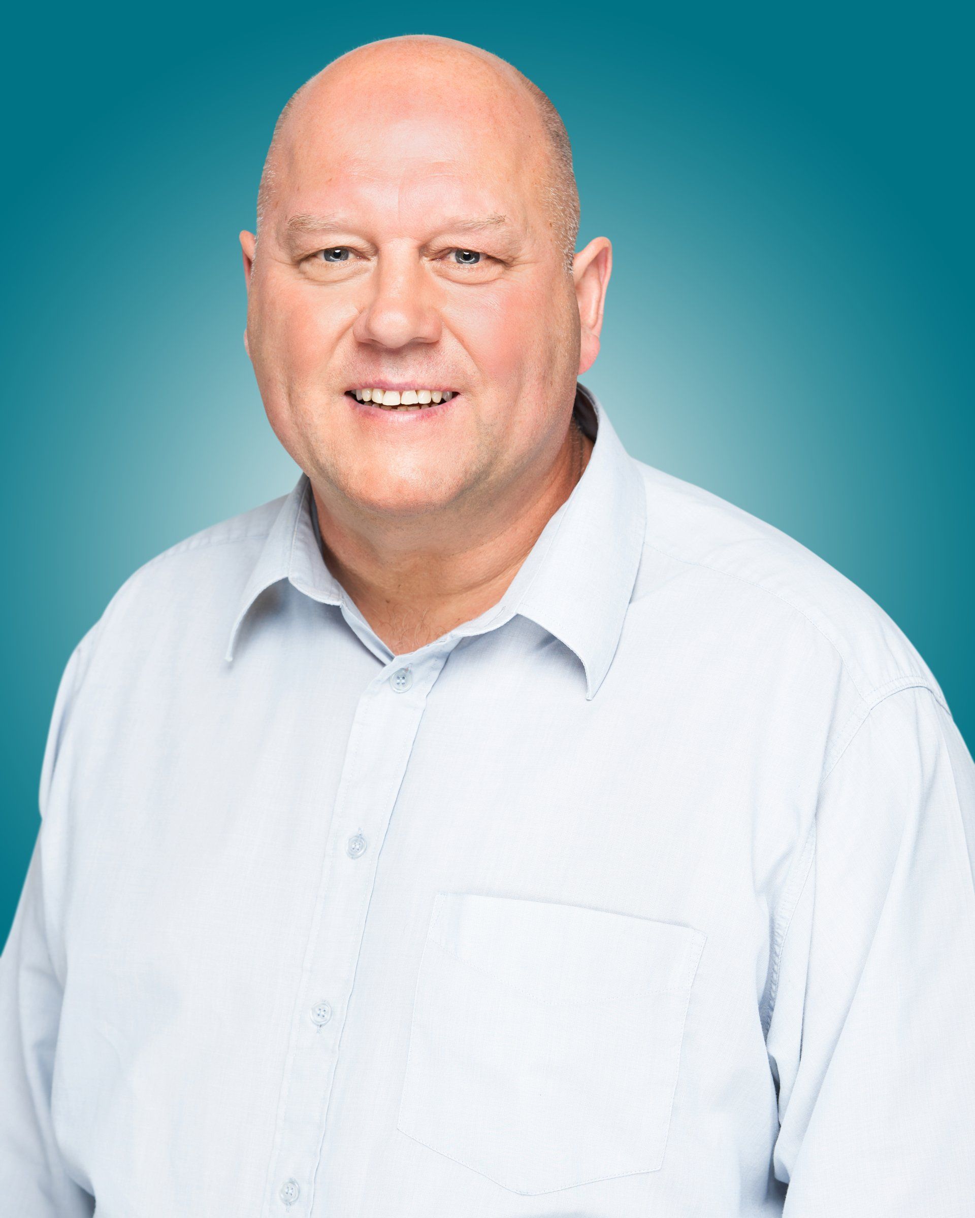 A bald man in a blue shirt is smiling for the camera.