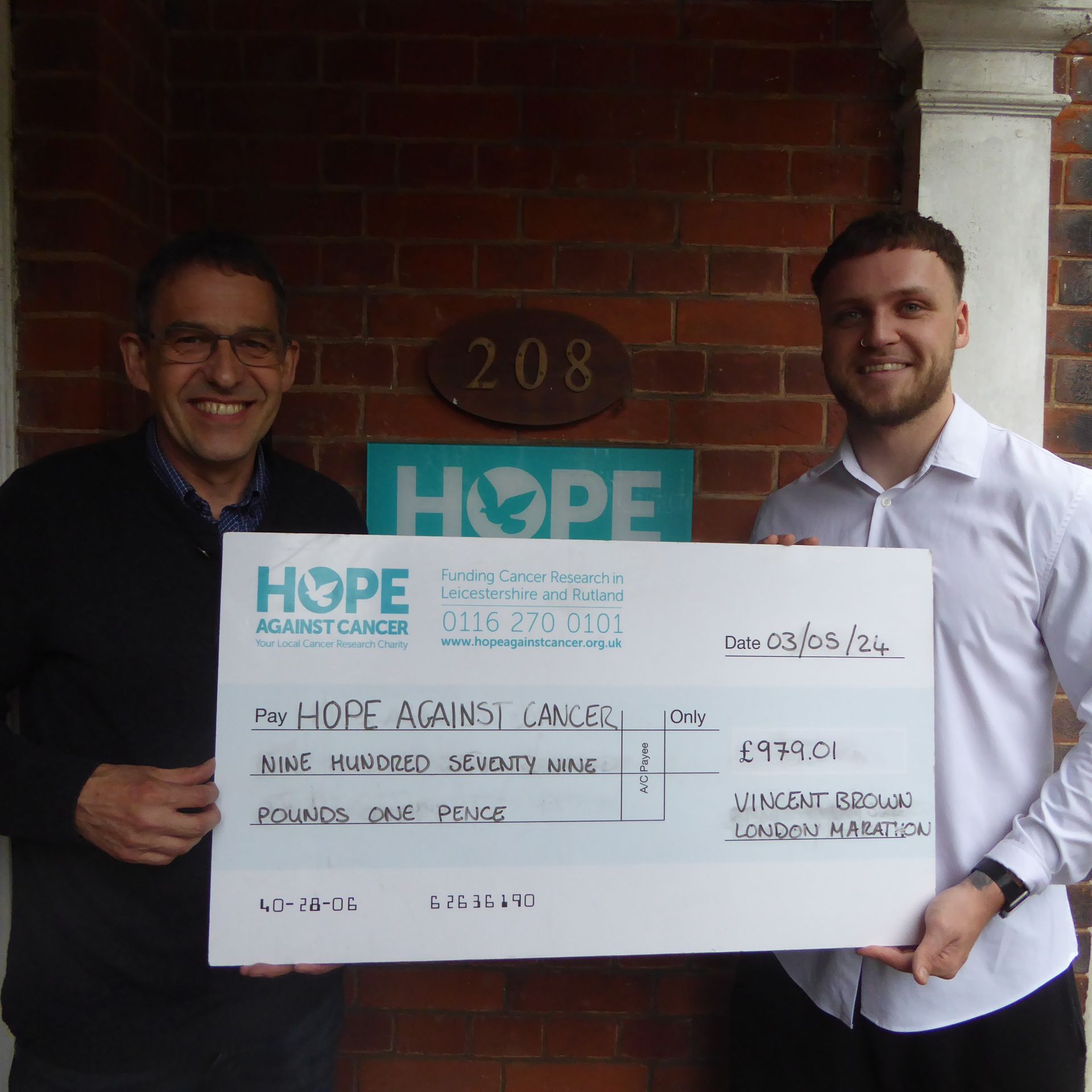 Two men holding a cheque for hope against cancer