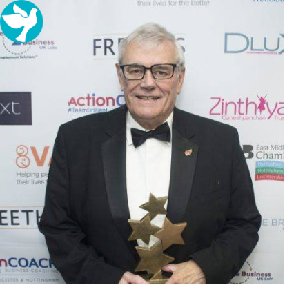 A man in a tuxedo and bow tie is holding a trophy.