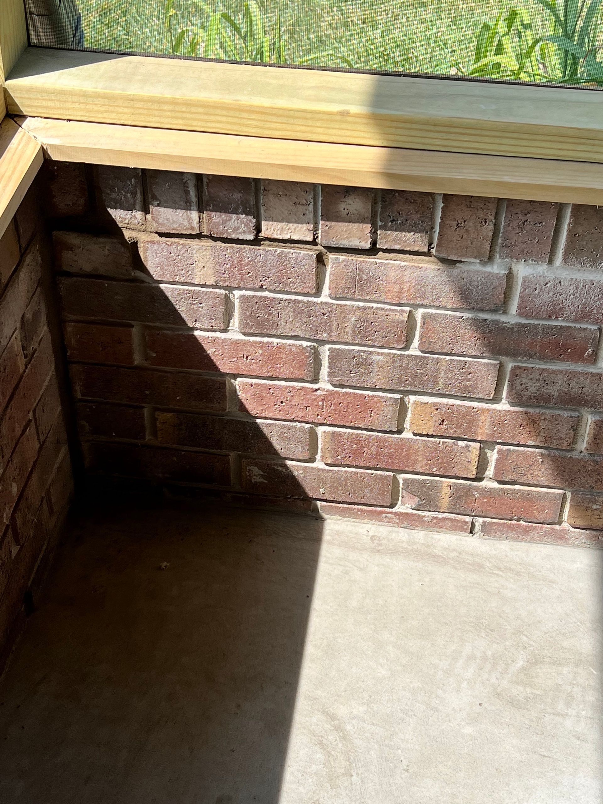 A brick wall with a wooden ledge on top of it.