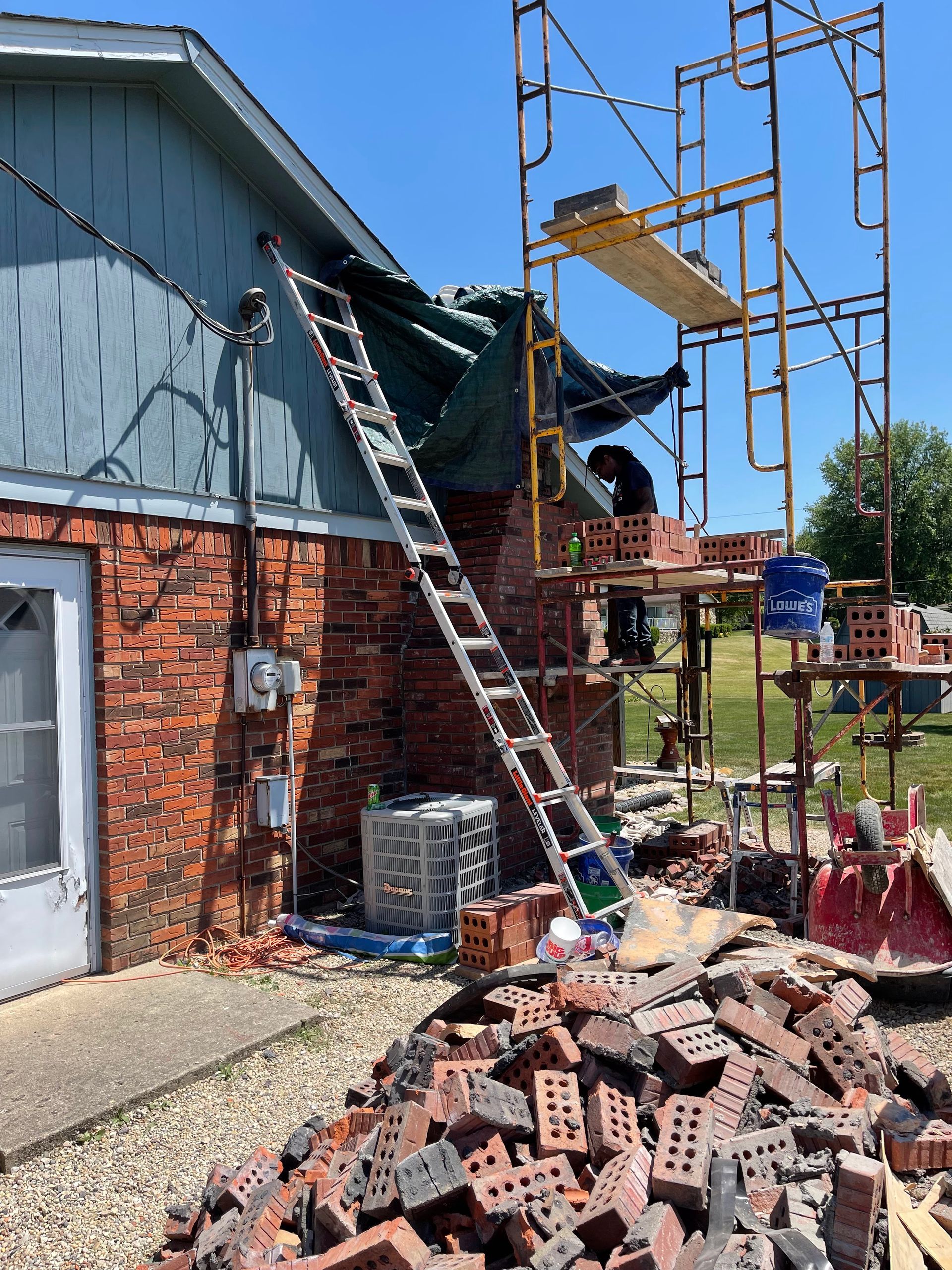 A ladder is sitting on top of a pile of bricks in front of a house.