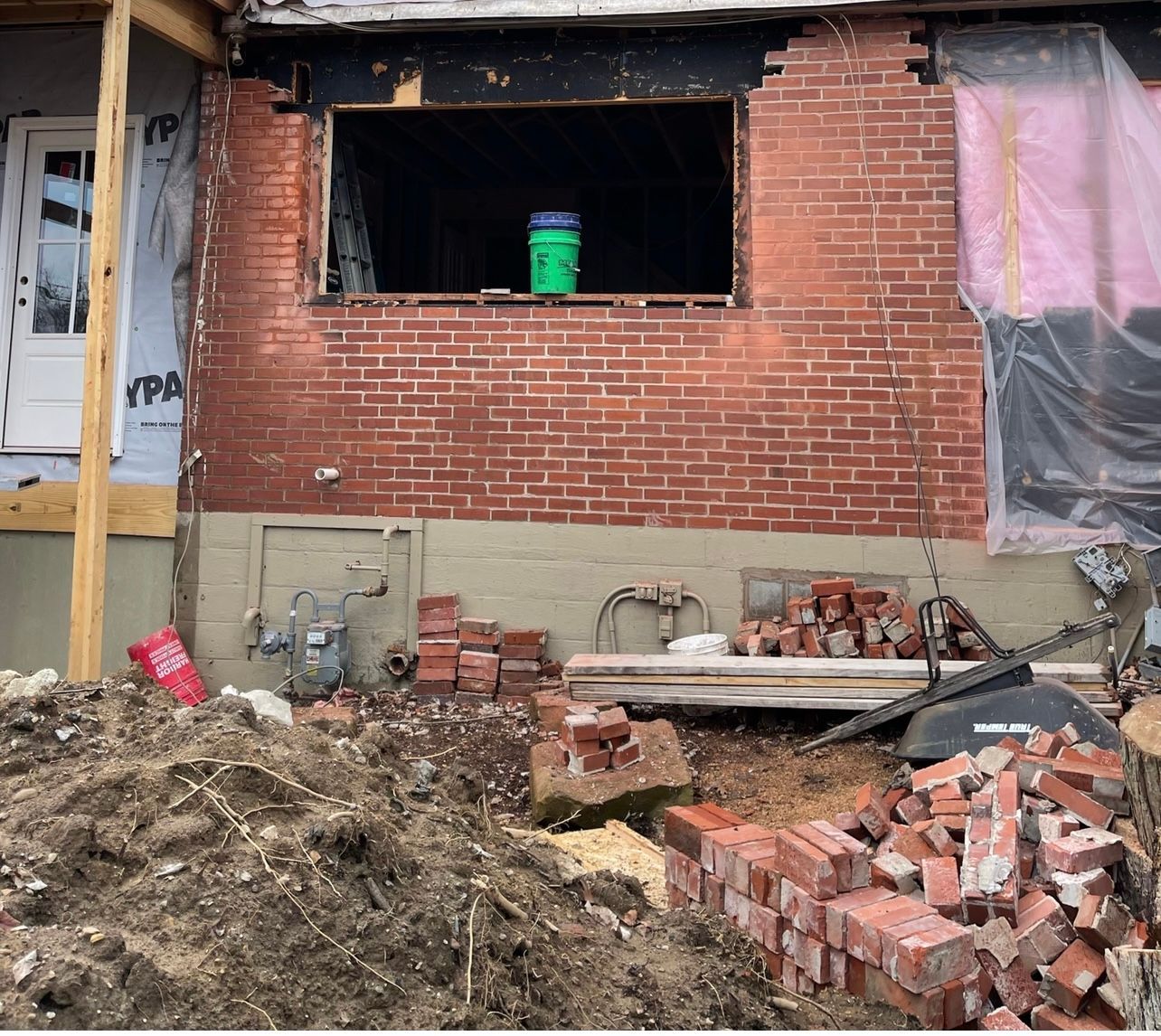 A pile of bricks sits in front of a brick building under construction