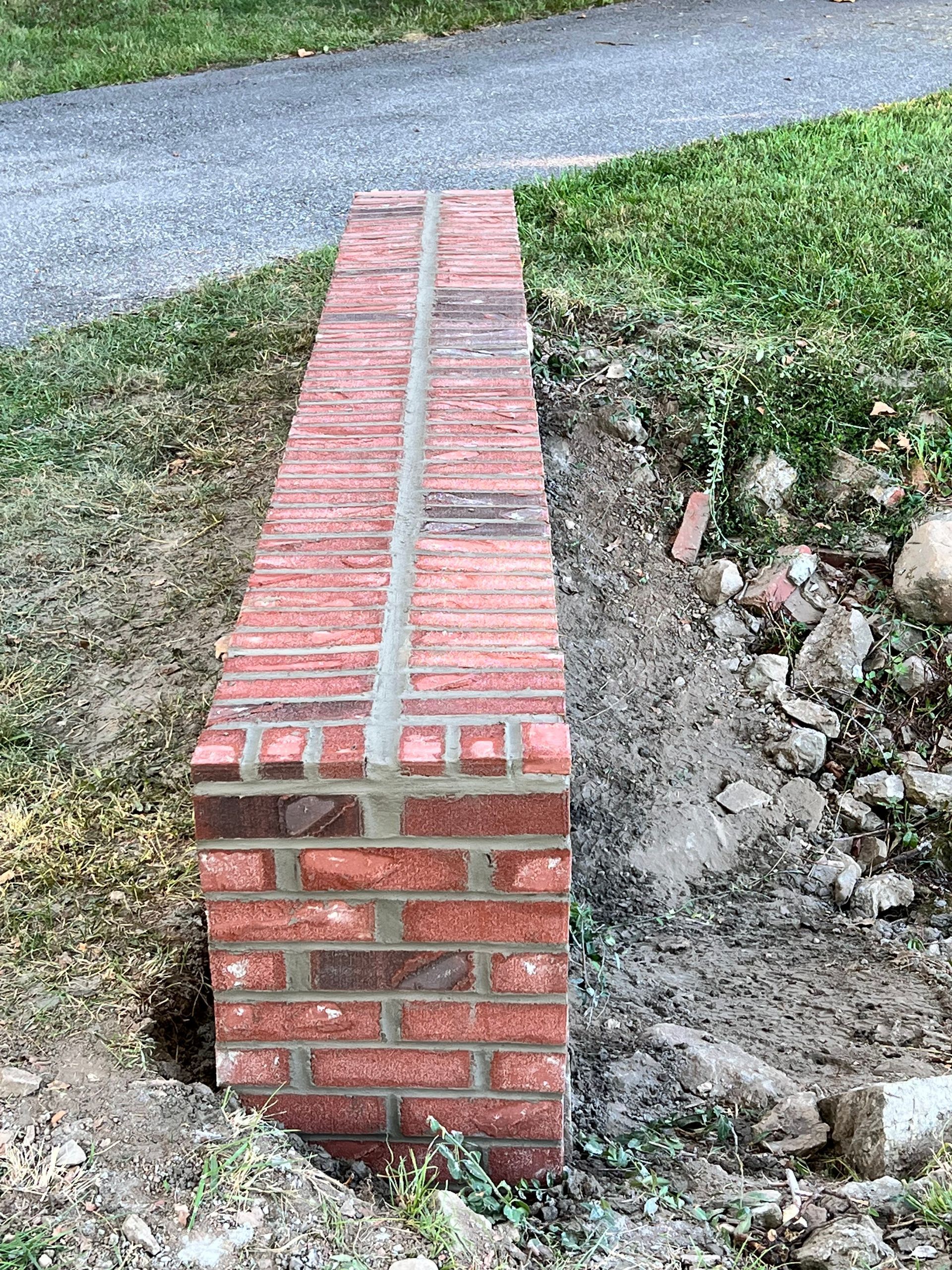 A brick wall is being built next to a dirt path.