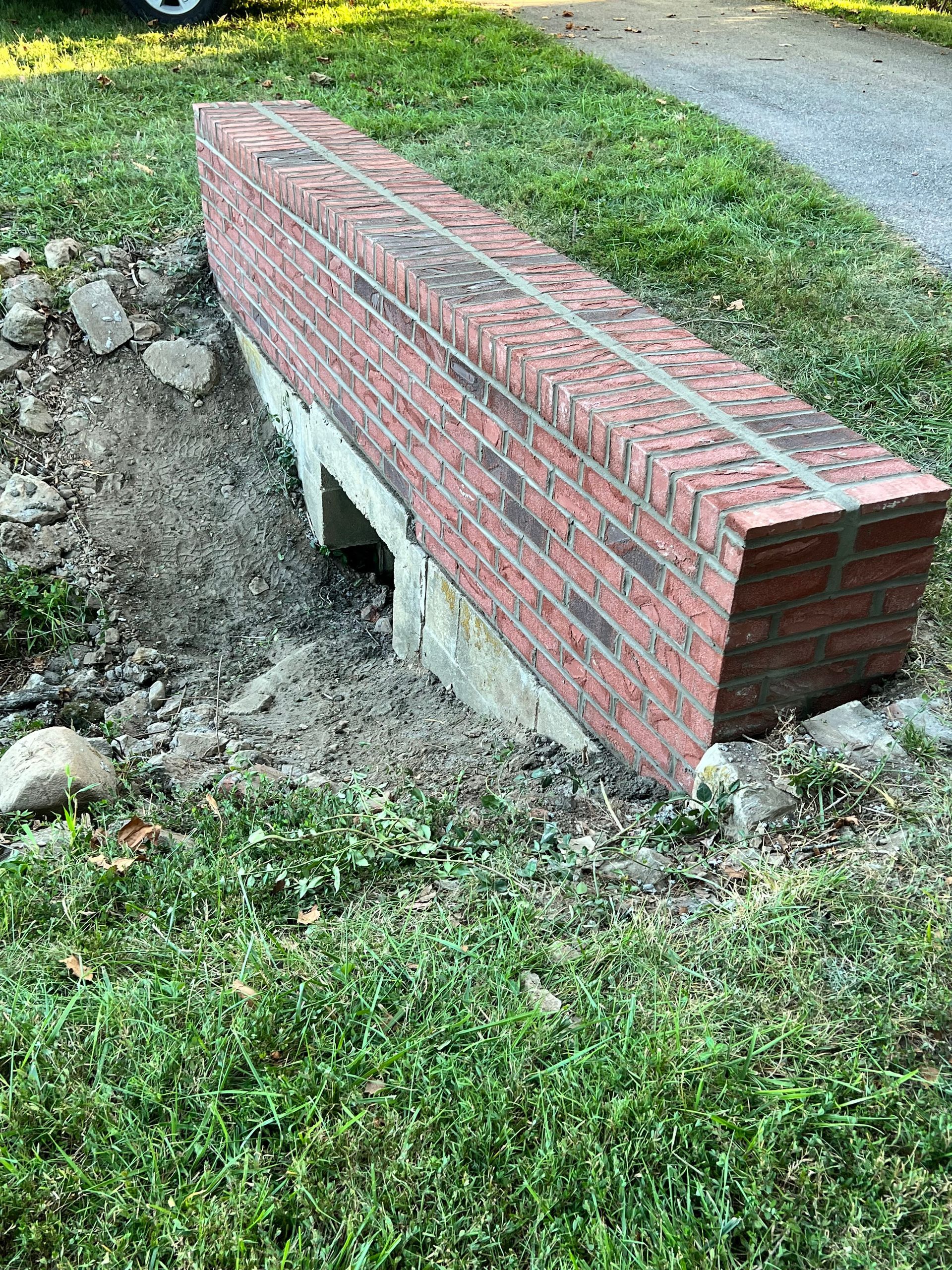 A brick bench is sitting in the middle of a grassy field.