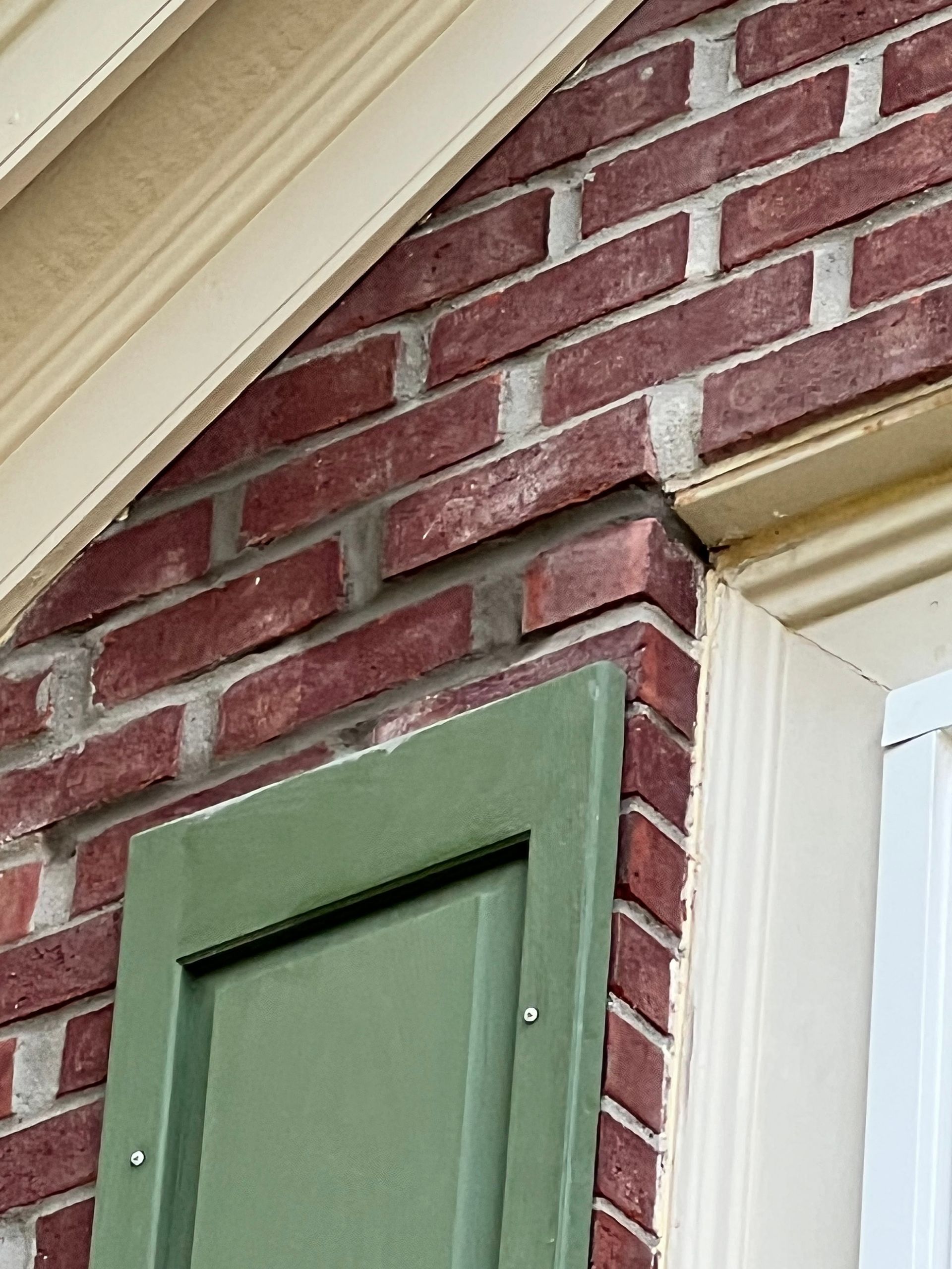 A brick wall with a green shutter on it