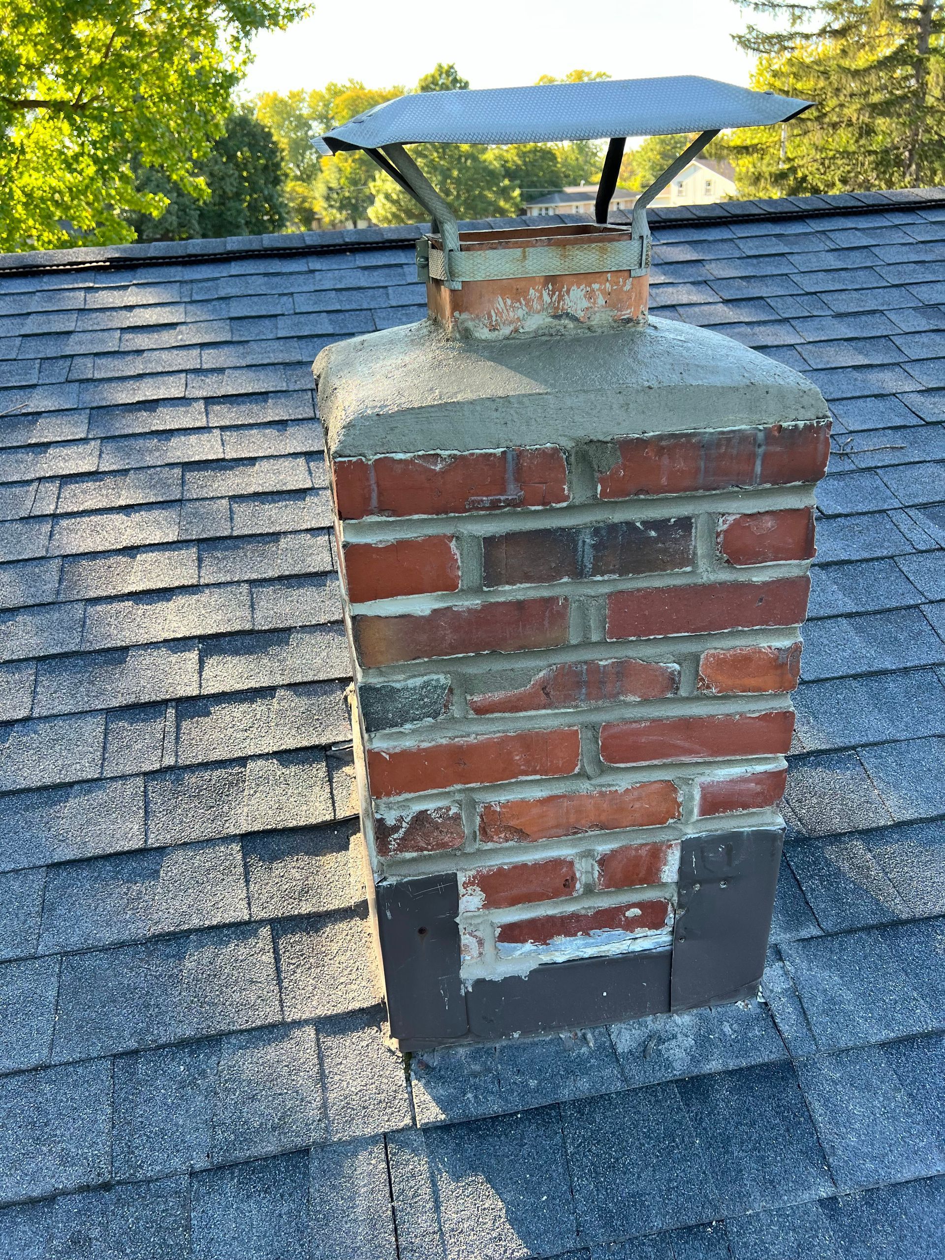A brick chimney is sitting on top of a roof.