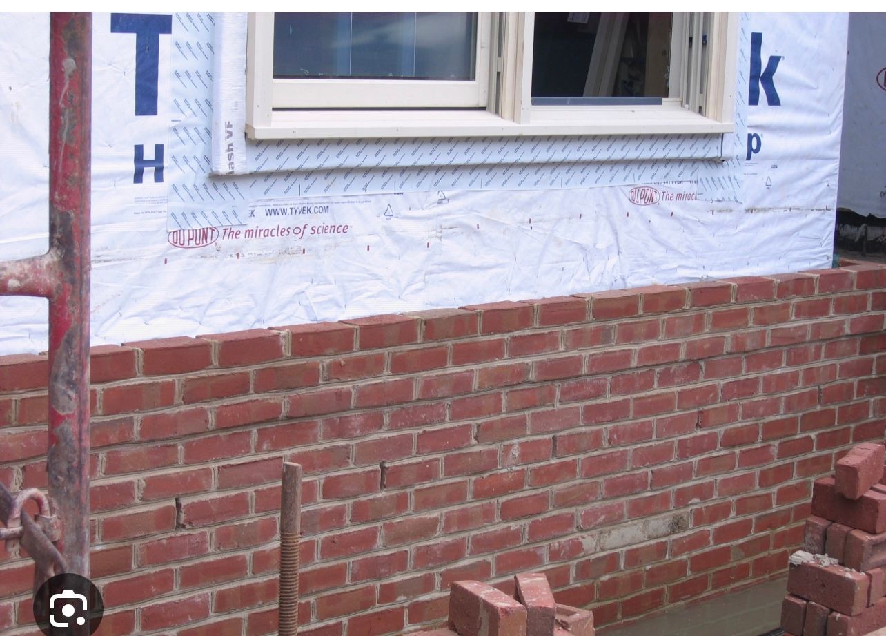 A brick wall with a window and the letter k on it