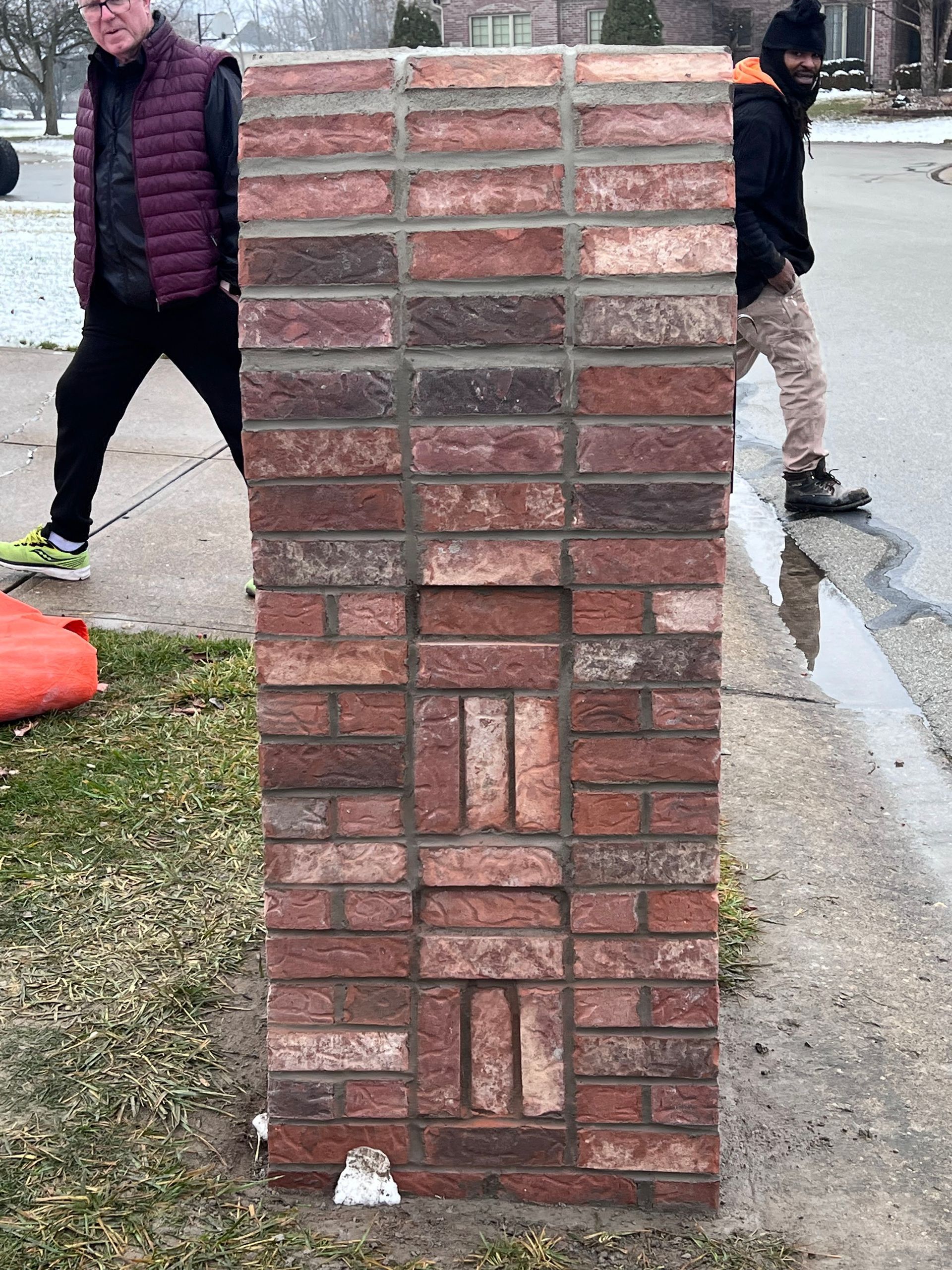 A man is standing next to a brick wall.