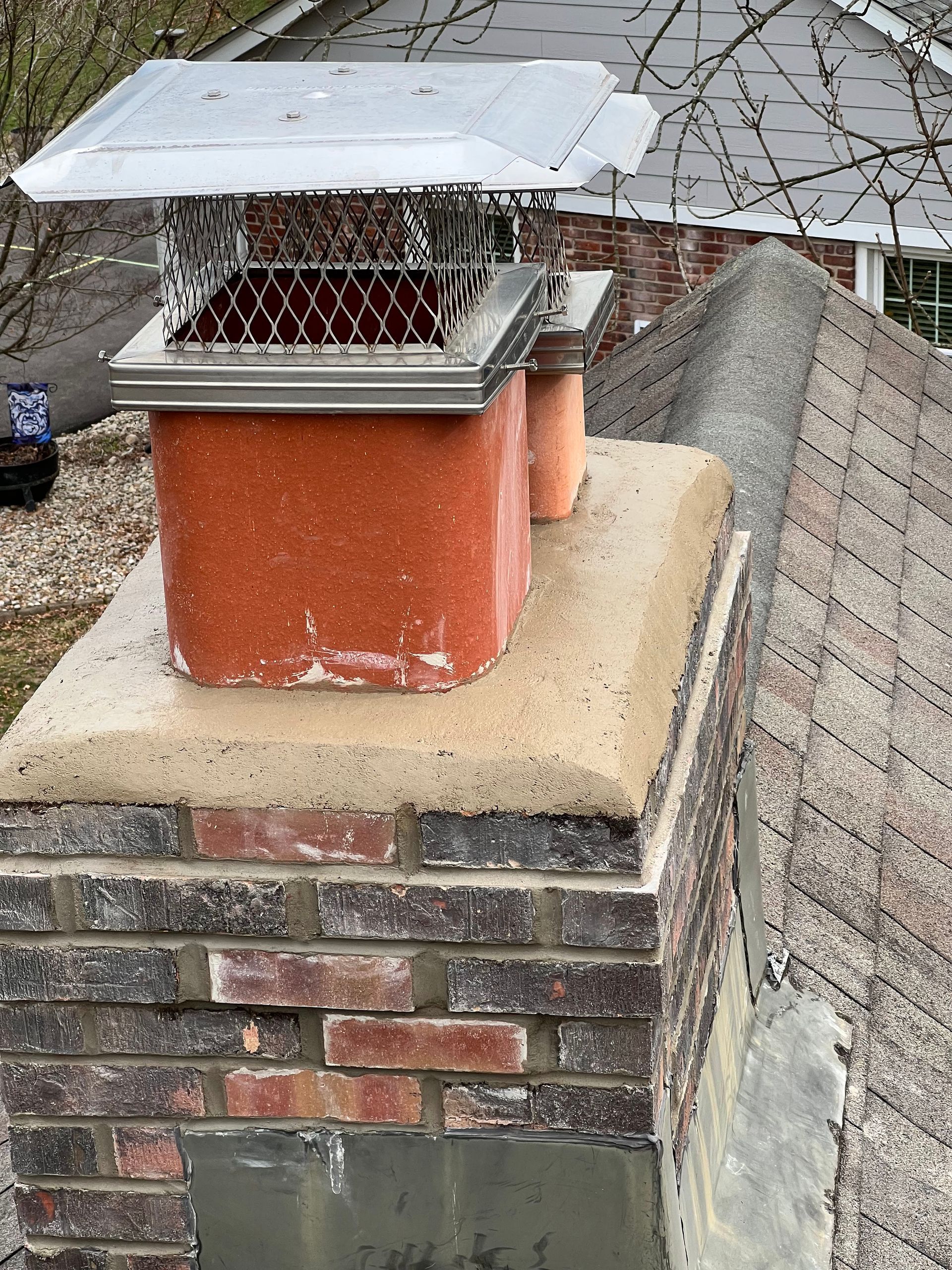 A chimney on top of a brick chimney on a roof
