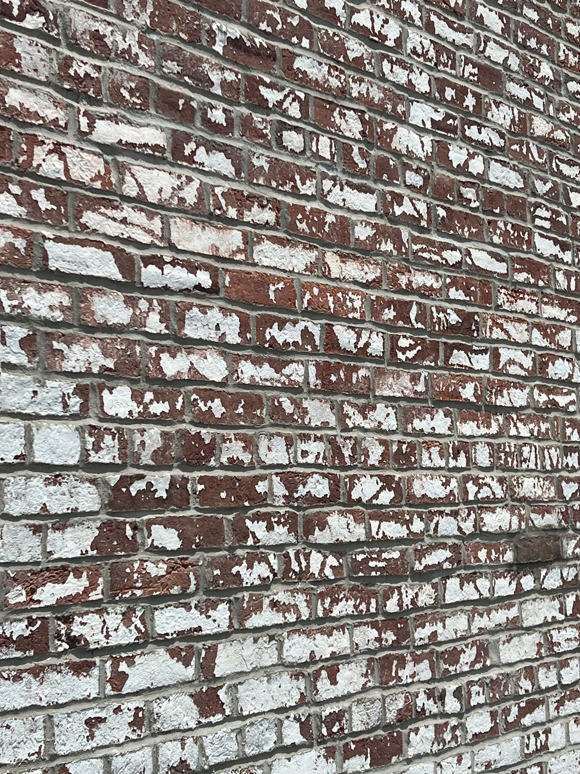 A close up of a brick wall with white paint on it.