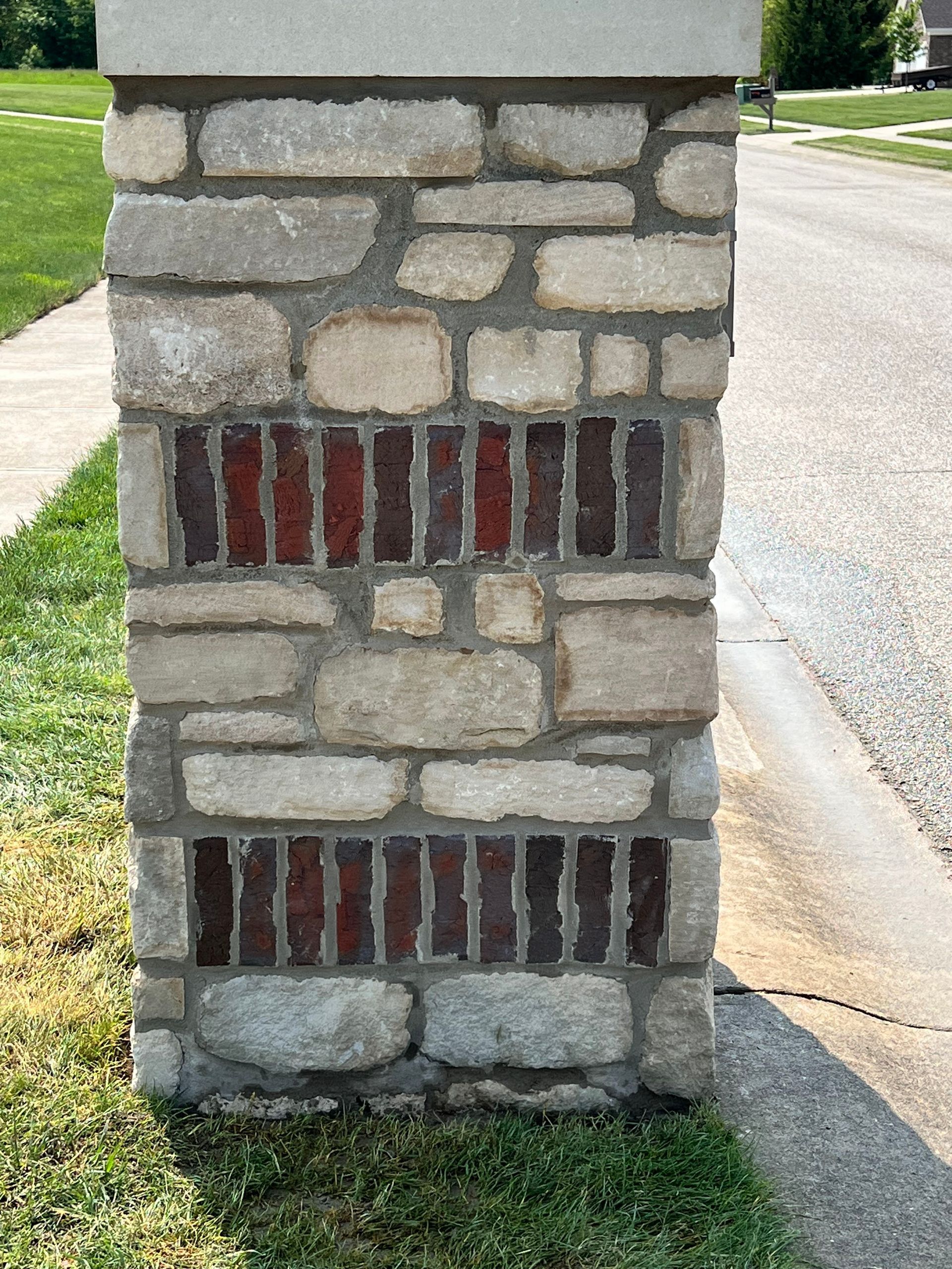 A stone pillar with bricks on the side of it