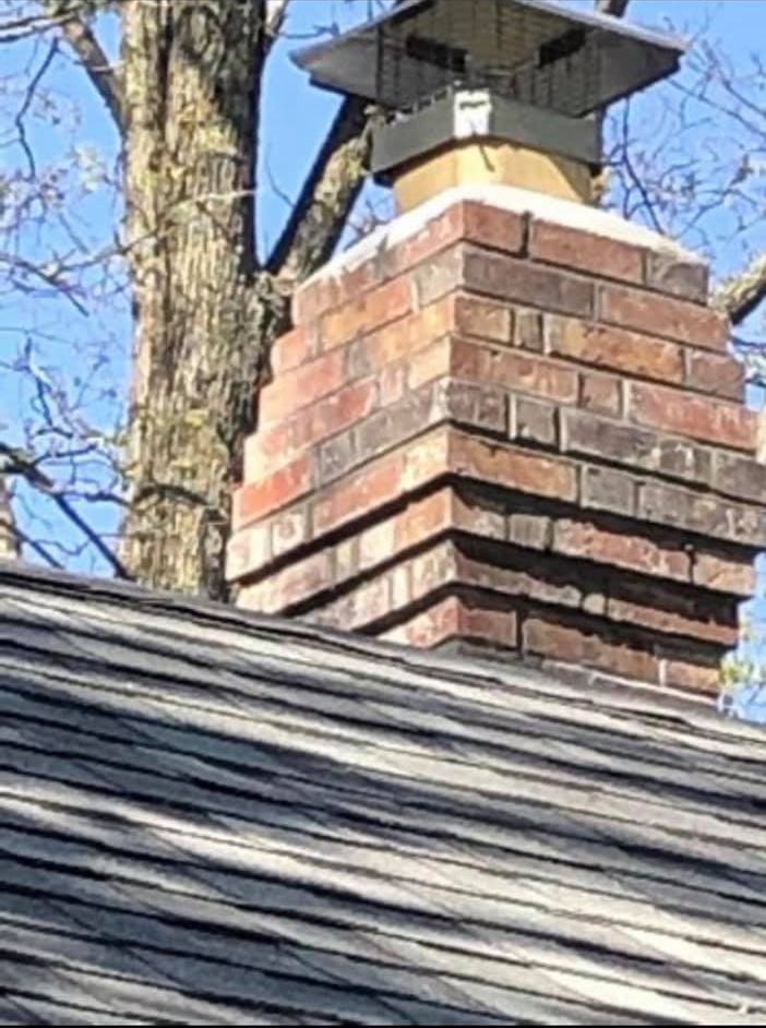 A close up of a brick chimney on top of a wooden roof.
