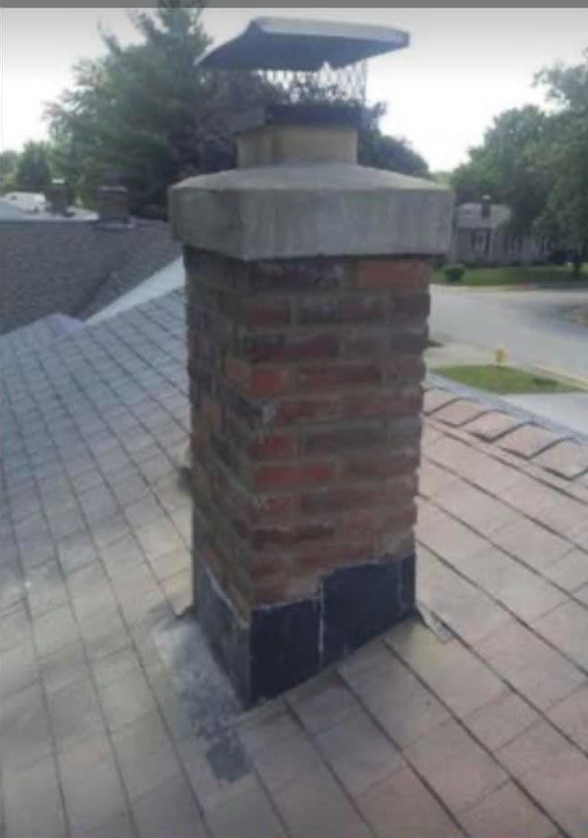 A chimney on top of a roof with trees in the background.
