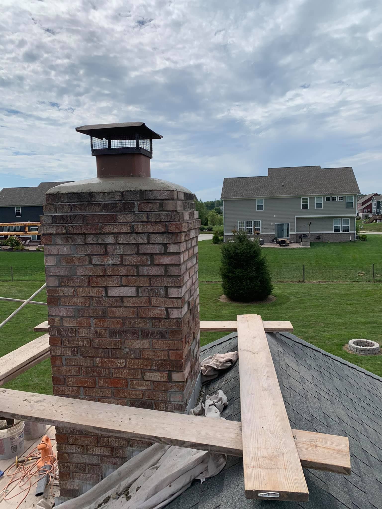 A brick chimney is sitting on top of a roof in a residential area.