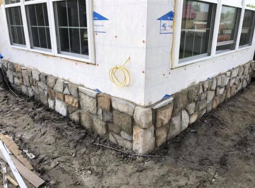 A house is being built with stone siding and windows.
