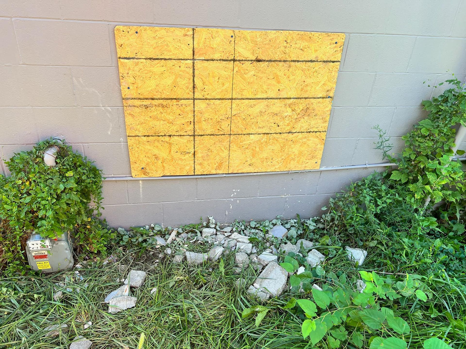 A window on the side of a building has been boarded up.