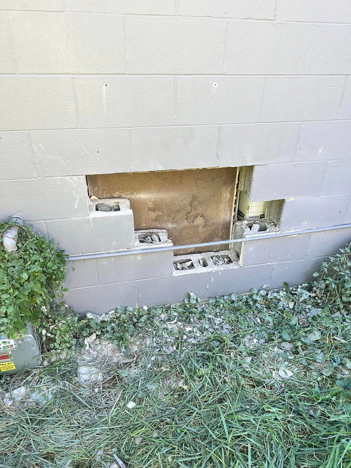 A brick wall with a hole in it and a window.