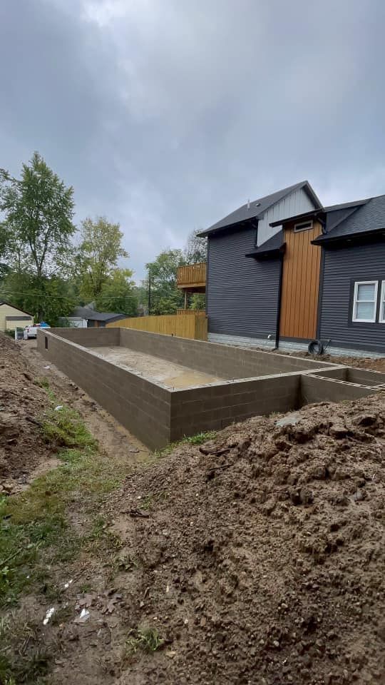 A large house is being built in the middle of a dirt field.