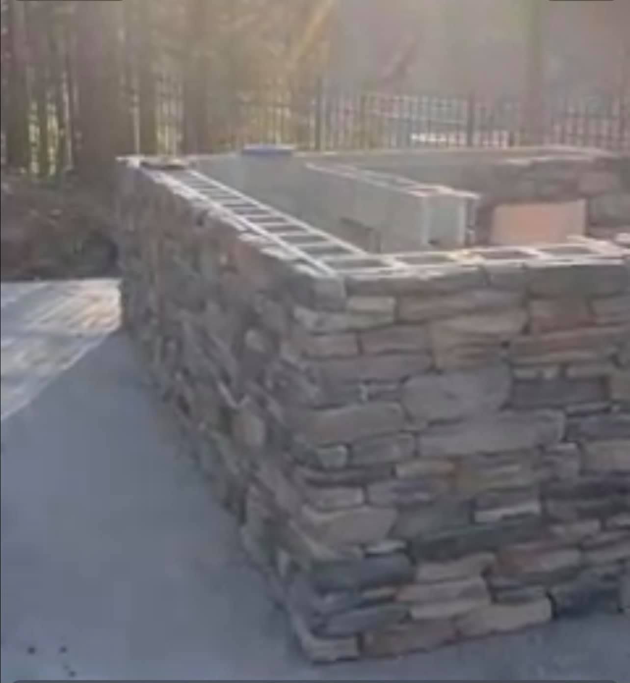 A large stone wall is being built on the side of a road.