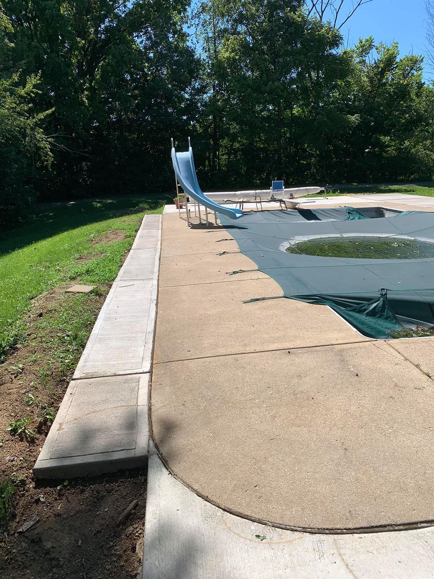 A slide is sitting next to a pool in a park.