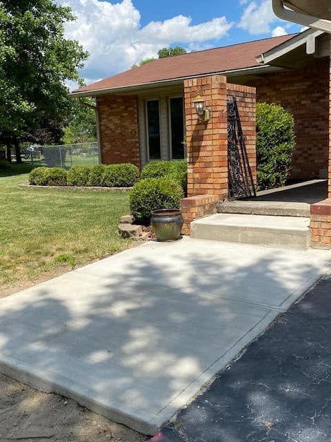 A brick house with a concrete walkway leading to the front door.