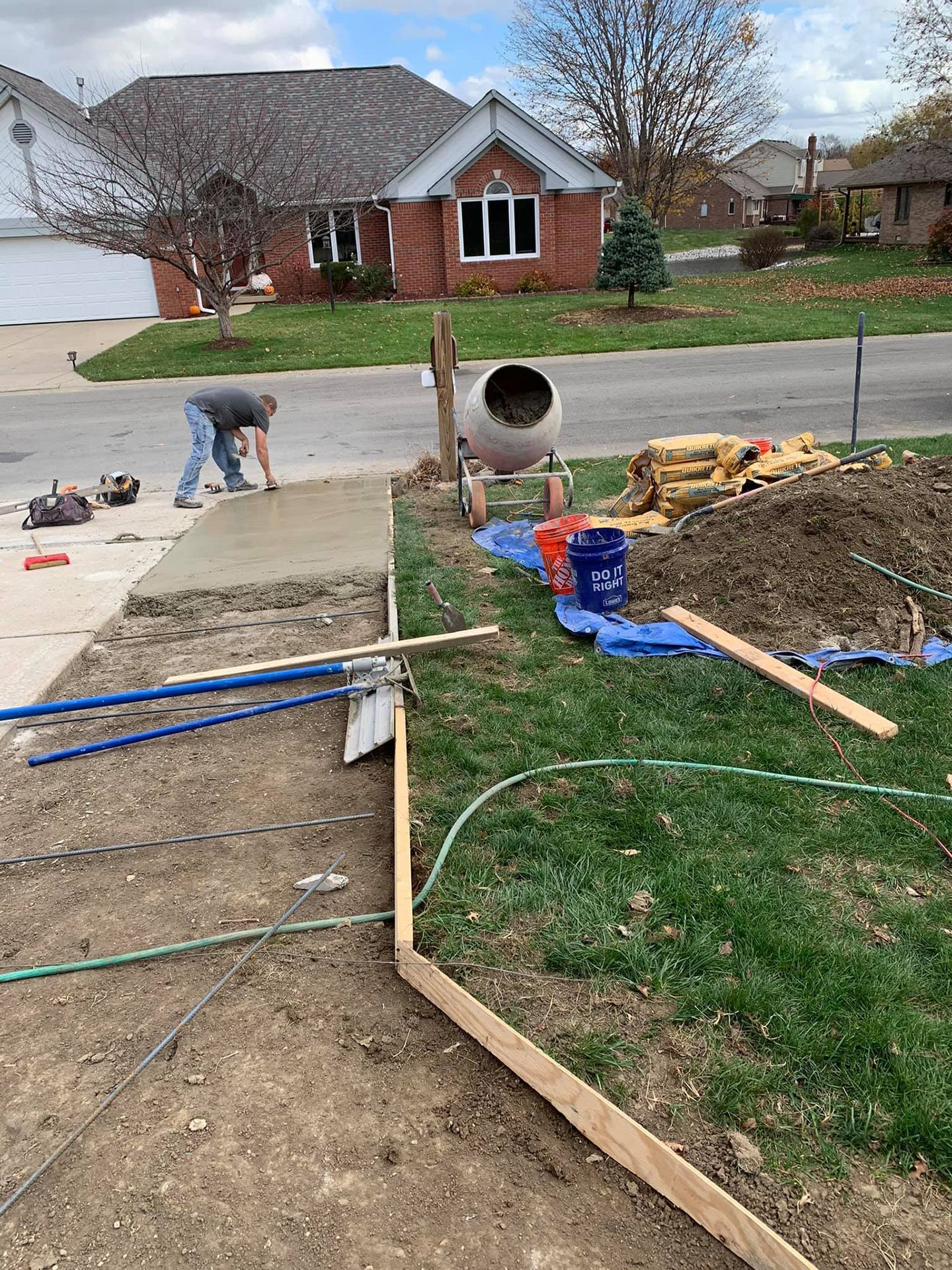 A man is working on a sidewalk in front of a house.