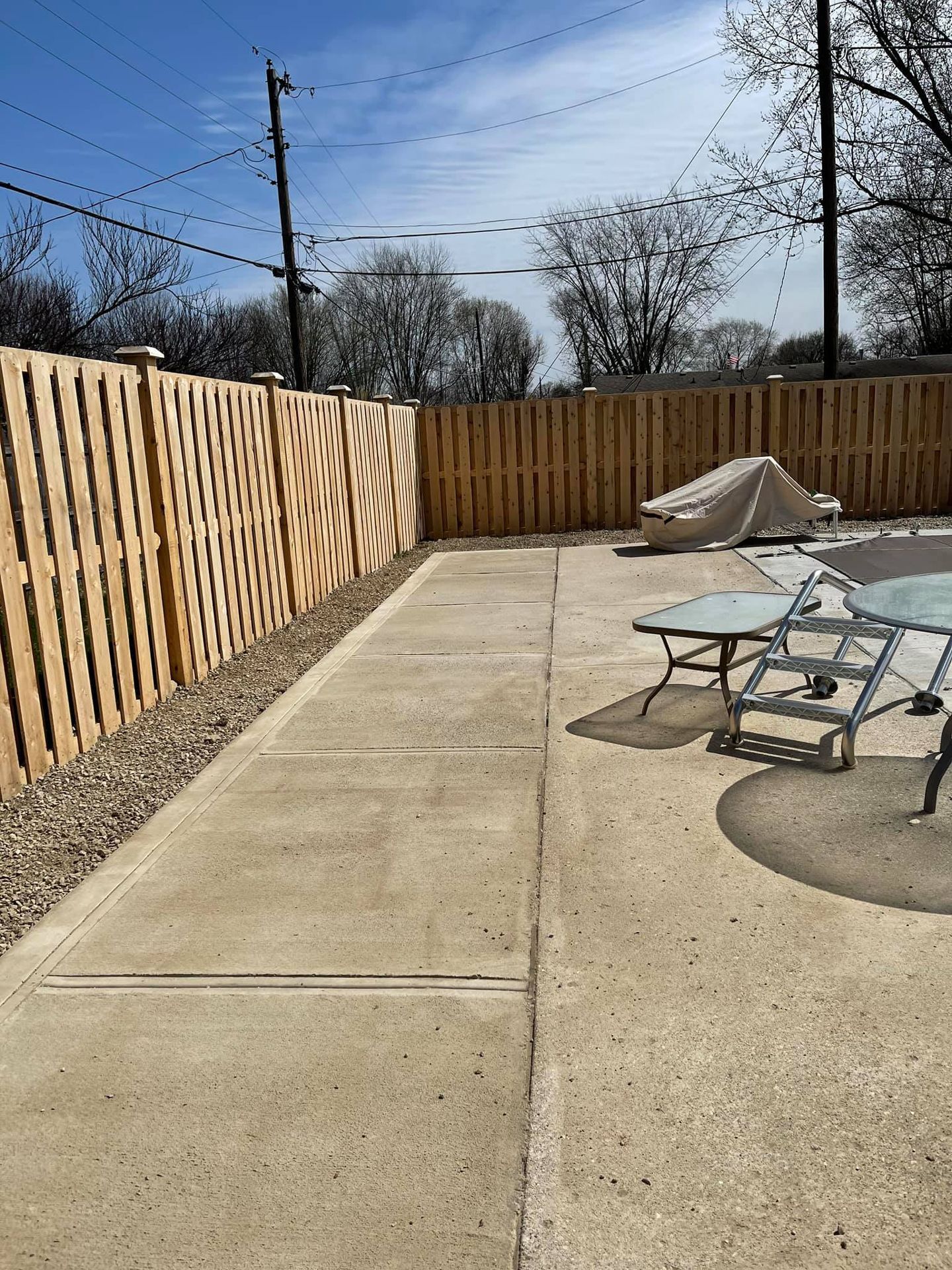 A patio with a wooden fence and a table and chairs.
