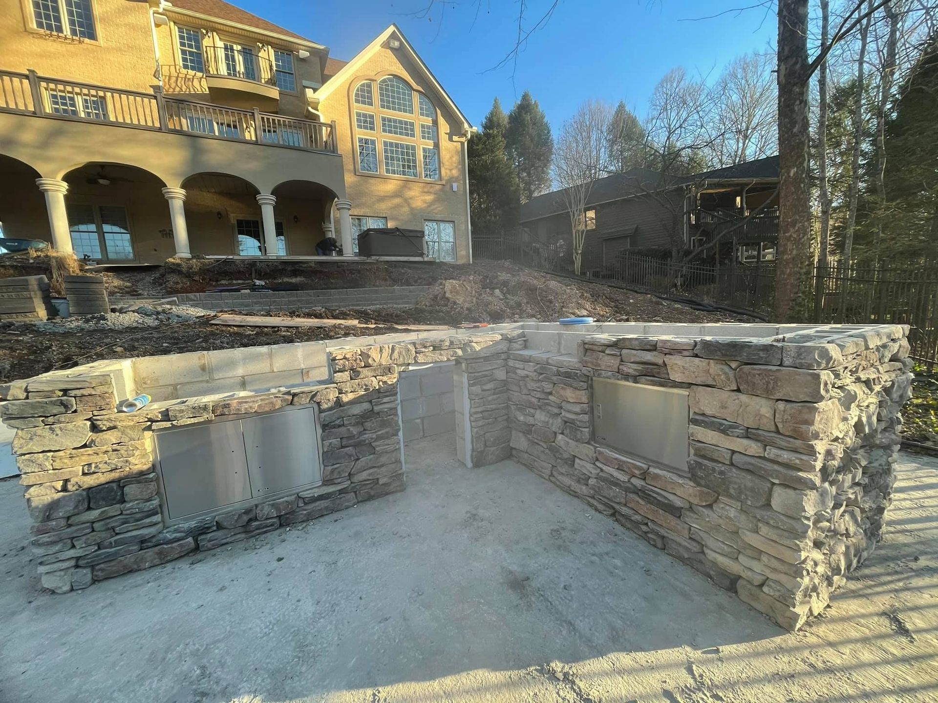 A large house is being built next to a stone wall.