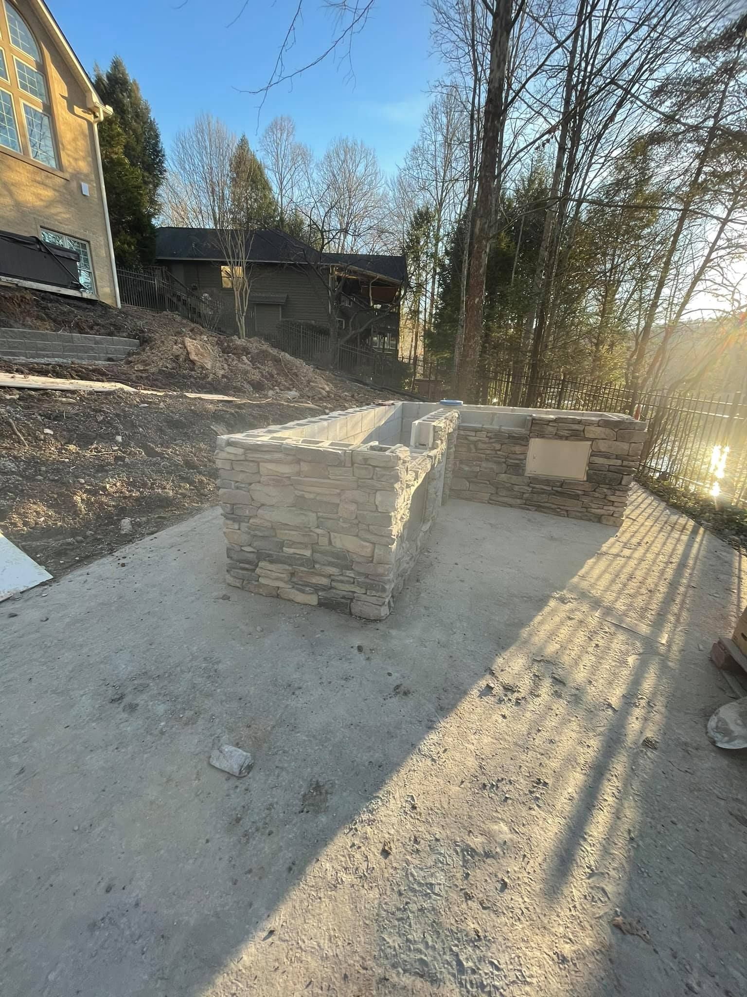 A brick wall is being built in the backyard of a house.