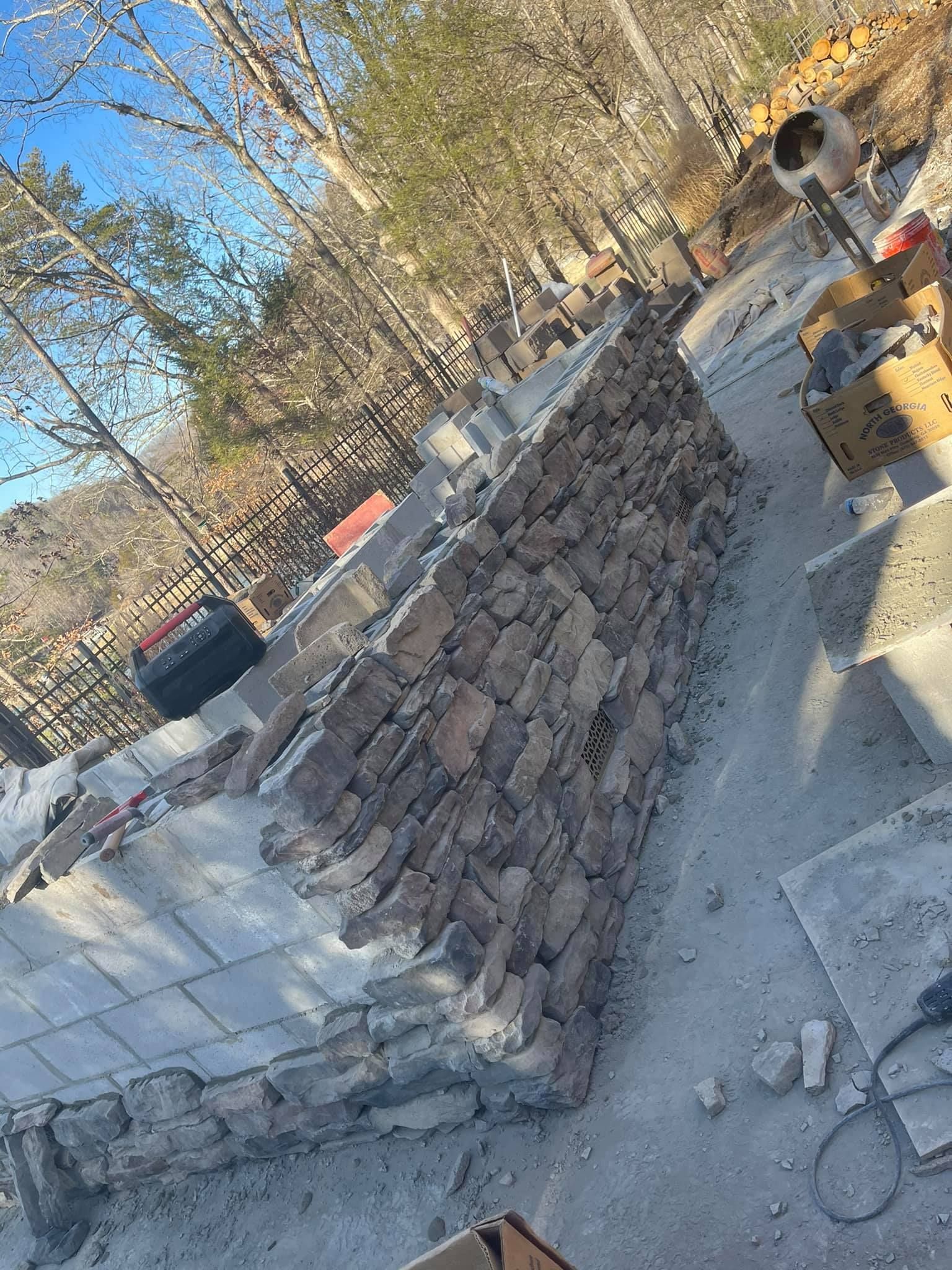 A stone wall is being built in the middle of a forest.