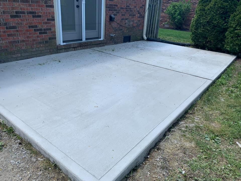 A concrete patio in front of a brick house.