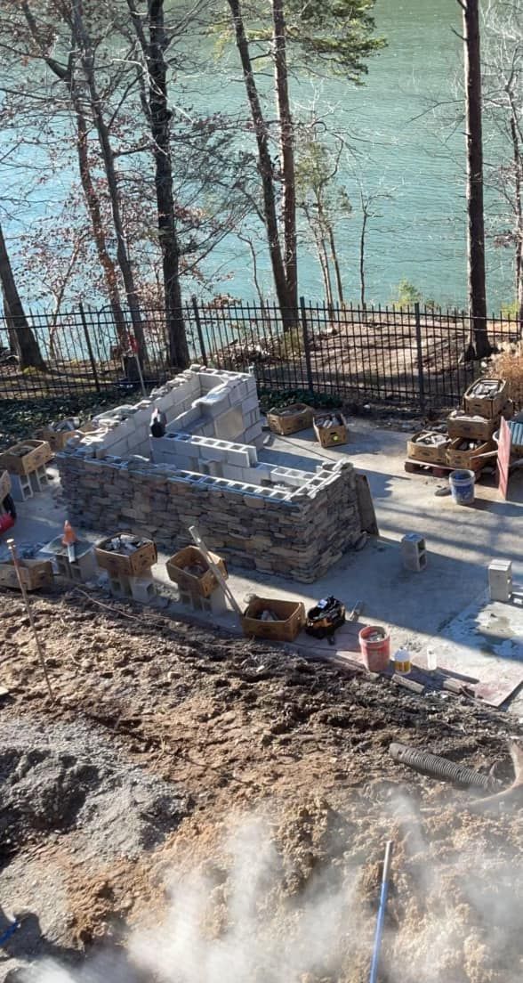 A large stone wall is being built next to a body of water.