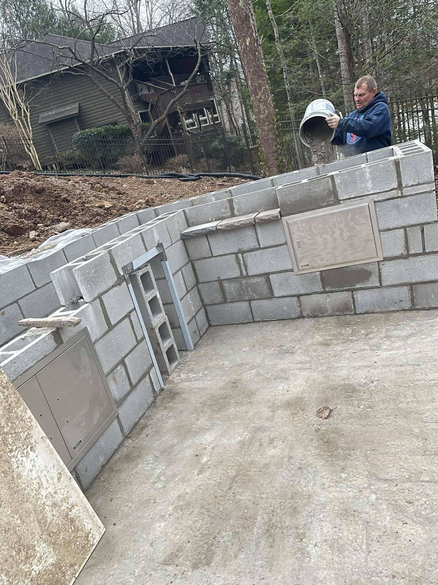 A man is pouring concrete into a brick wall.