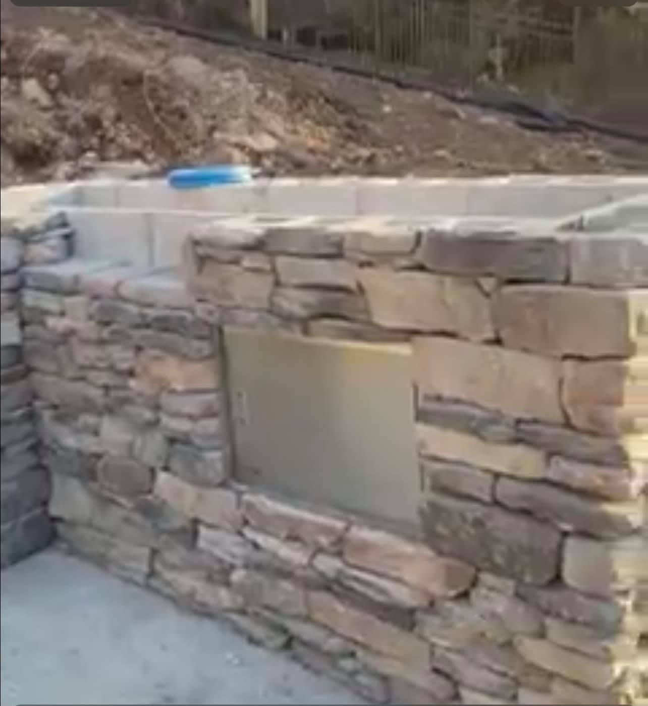 A stone wall is being built in a backyard.