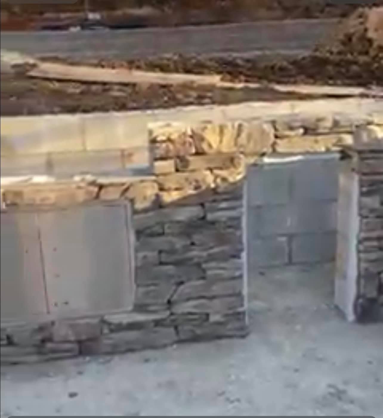 A stone wall is being built on the side of a road.