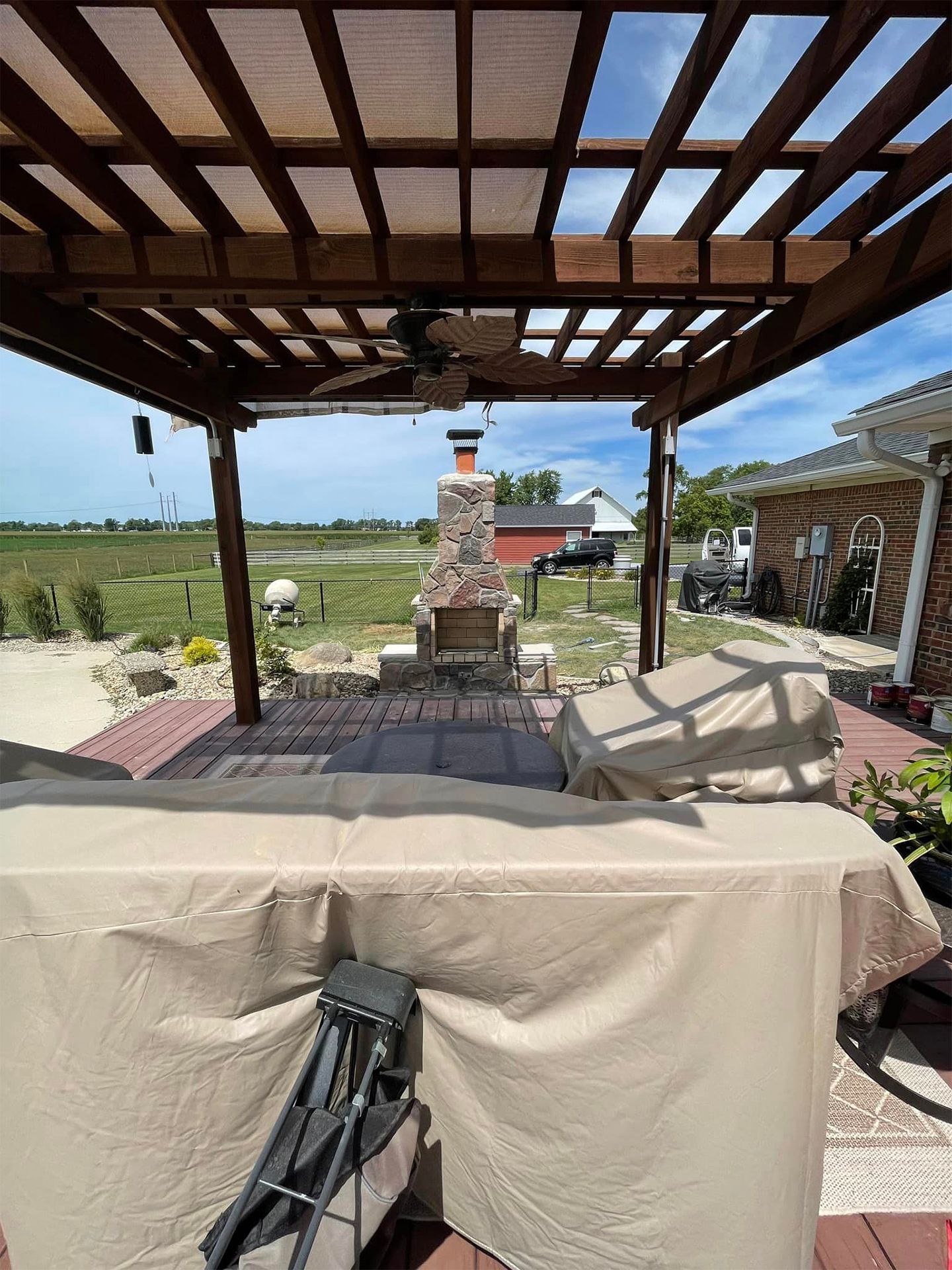 A pergola with a fireplace and a table underneath it.