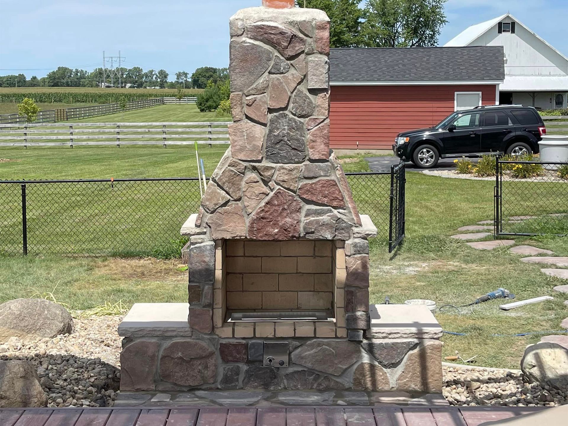 A stone fireplace is sitting on top of a wooden deck in front of a house.