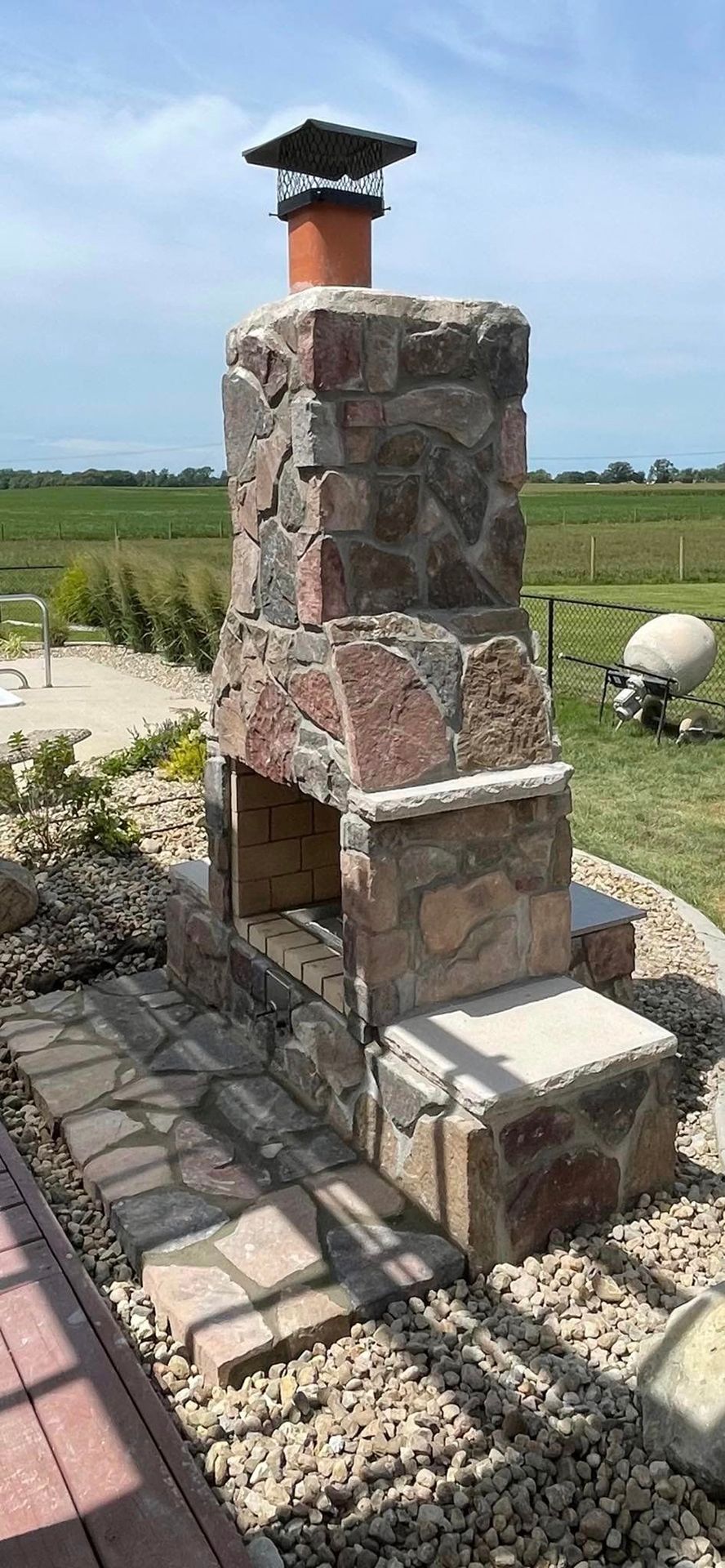 A stone fireplace is sitting in the middle of a lush green field.
